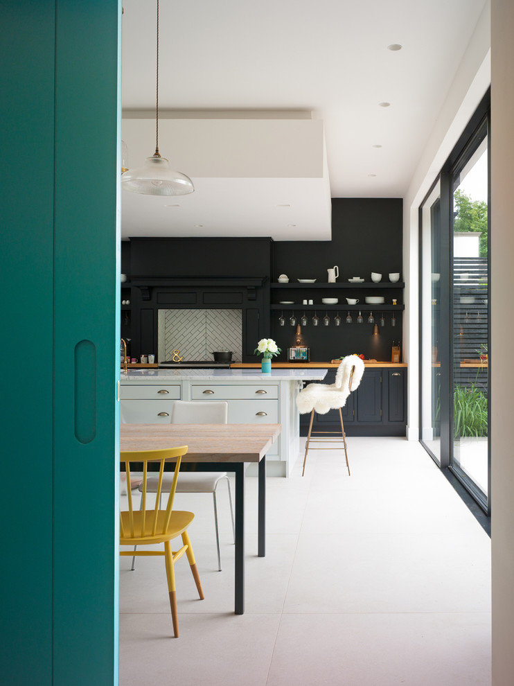 Inspiration for an eclectic l-shaped open plan kitchen in Kent with a drop-in sink, marble benchtops, a peninsula, flat-panel cabinets, white splashback, cement tile splashback, panelled appliances, ceramic floors and black cabinets.