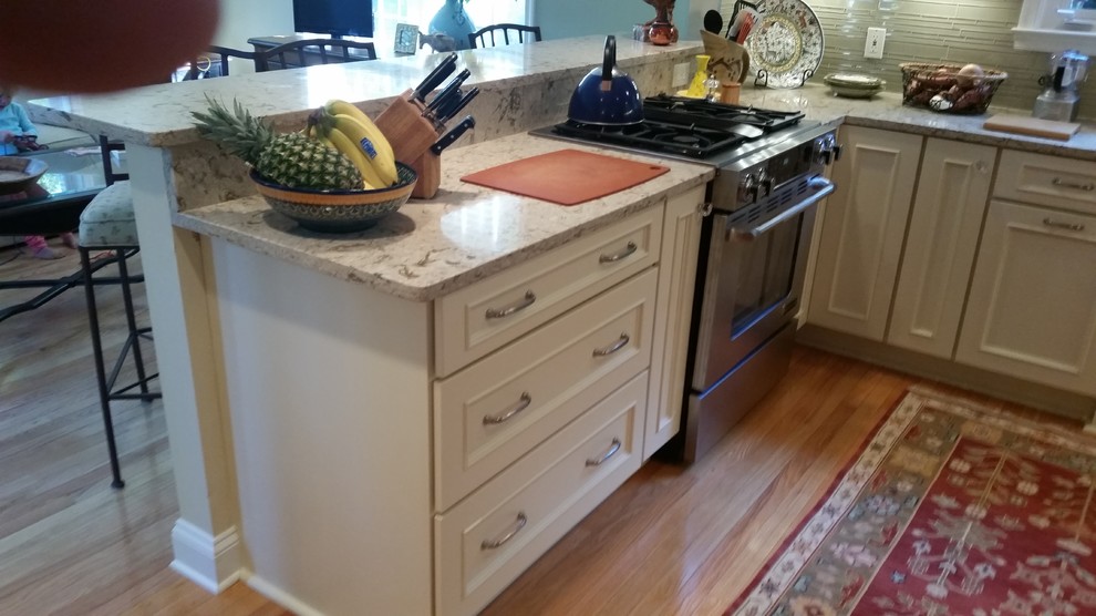 Example of a transitional kitchen design with flat-panel cabinets, white cabinets, quartz countertops and glass sheet backsplash