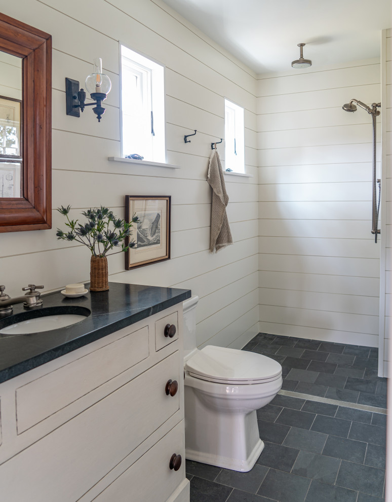 Mid-sized country 3/4 bathroom in Boston with a single vanity, planked wall panelling, an open shower, white walls, slate floors, grey floor, black benchtops, a built-in vanity, flat-panel cabinets, white cabinets, a one-piece toilet, an undermount sink, soapstone benchtops and an open shower.
