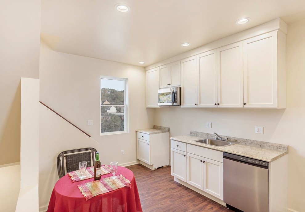 Inspiration for a small transitional galley brown floor eat-in kitchen remodel with a single-bowl sink, shaker cabinets, white cabinets, laminate countertops, beige backsplash, stainless steel appliances and no island