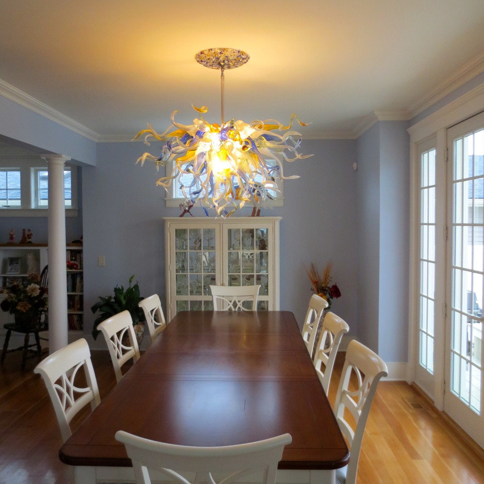 This is an example of a large arts and crafts open plan dining in New York with blue walls, light hardwood floors, a corner fireplace and a wood fireplace surround.