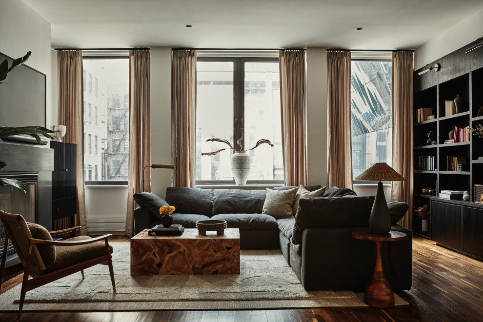 Пример оригинального дизайна: гостиная комната в стиле неоклассика (современная классика) с бежевыми стенами, темным паркетным полом, стандартным камином, телевизором на стене и коричневым полом