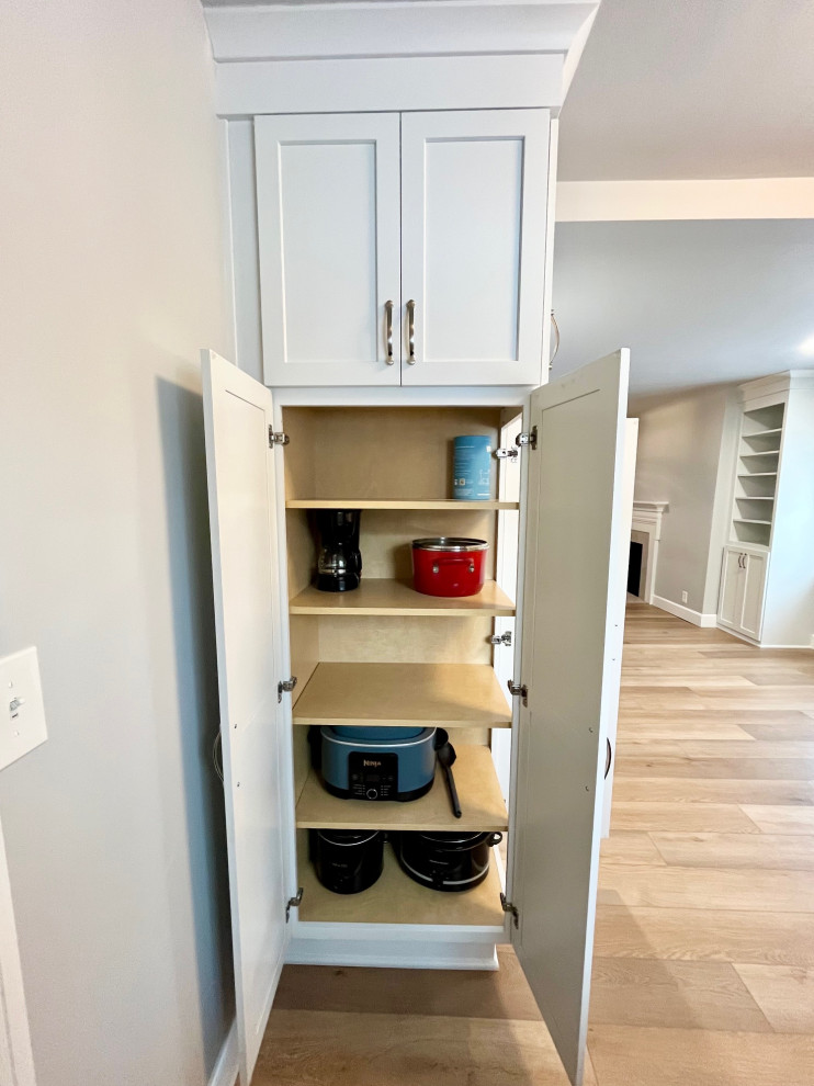 Inspiration for a mid-sized transitional u-shaped vinyl floor and brown floor eat-in kitchen remodel with an undermount sink, shaker cabinets, white cabinets, quartz countertops, white backsplash, ceramic backsplash, stainless steel appliances, no island and white countertops