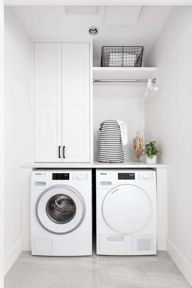 Inspiration for a small transitional single-wall laundry cupboard in Vancouver with recessed-panel cabinets, white cabinets, quartzite benchtops, porcelain floors, a side-by-side washer and dryer, grey floor and white benchtop.