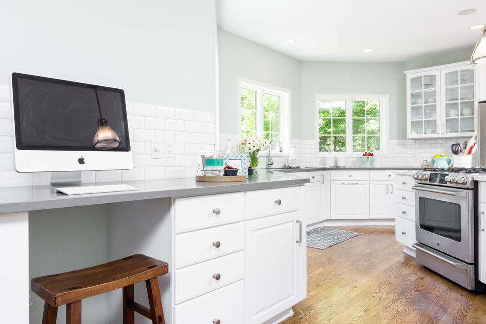 Example of a large transitional u-shaped medium tone wood floor and brown floor eat-in kitchen design in Detroit with raised-panel cabinets, white cabinets, quartz countertops, white backsplash, ceramic backsplash, an island, an undermount sink and white appliances