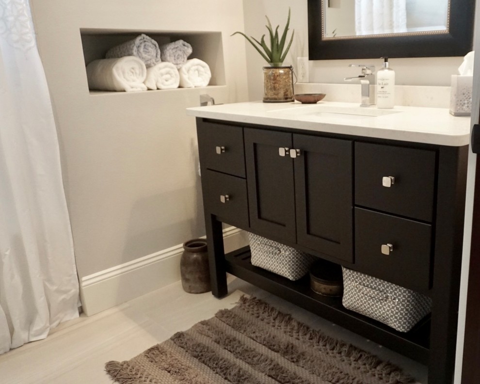 Inspiration for a small transitional gray tile and ceramic tile ceramic tile drop-in bathtub remodel in Cedar Rapids with furniture-like cabinets, black cabinets, a one-piece toilet, gray walls, an undermount sink and quartz countertops