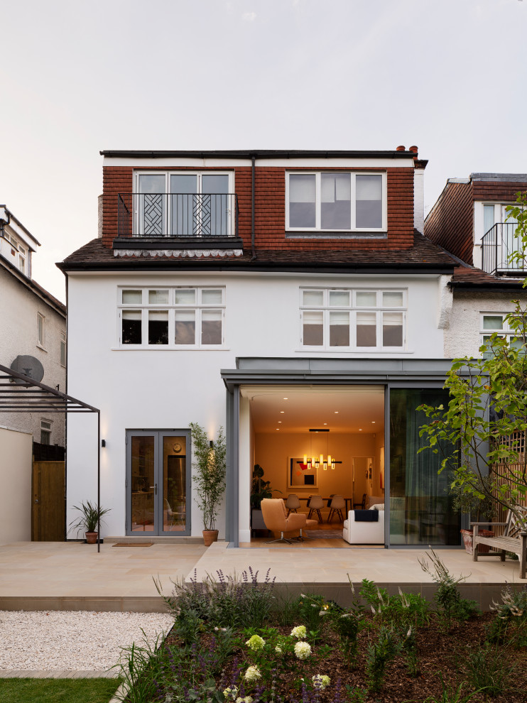 Photo of a transitional three-storey white house exterior in London with mixed siding.