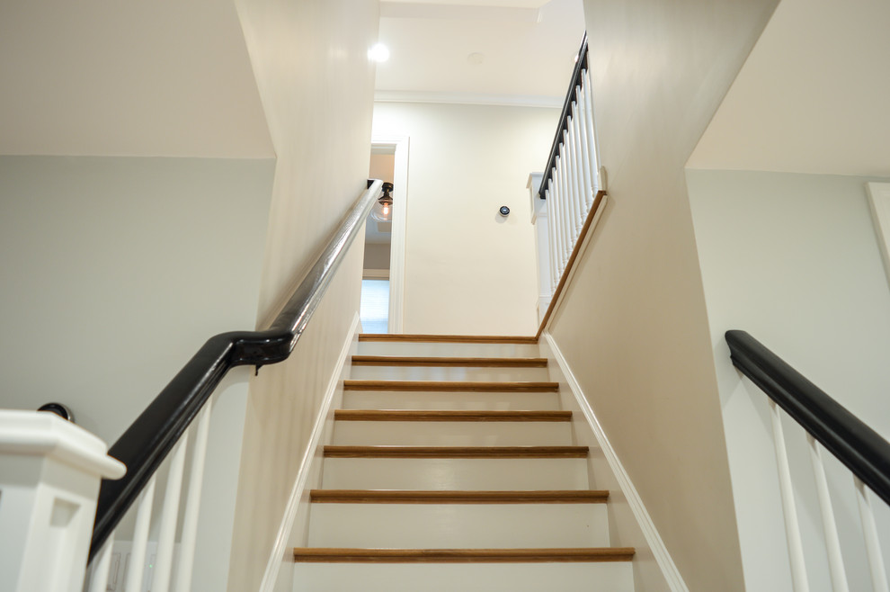This is an example of a mid-sized arts and crafts wood straight staircase in Boston with painted wood risers and wood railing.