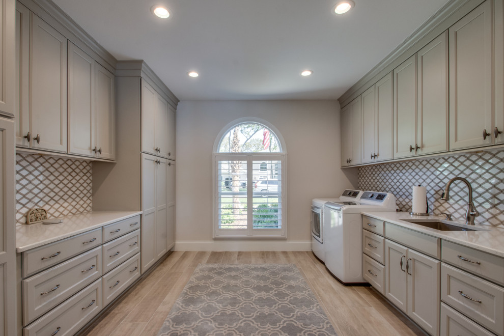 This is an example of a large transitional dedicated laundry room in Other with an undermount sink, recessed-panel cabinets, a side-by-side washer and dryer and beige floor.