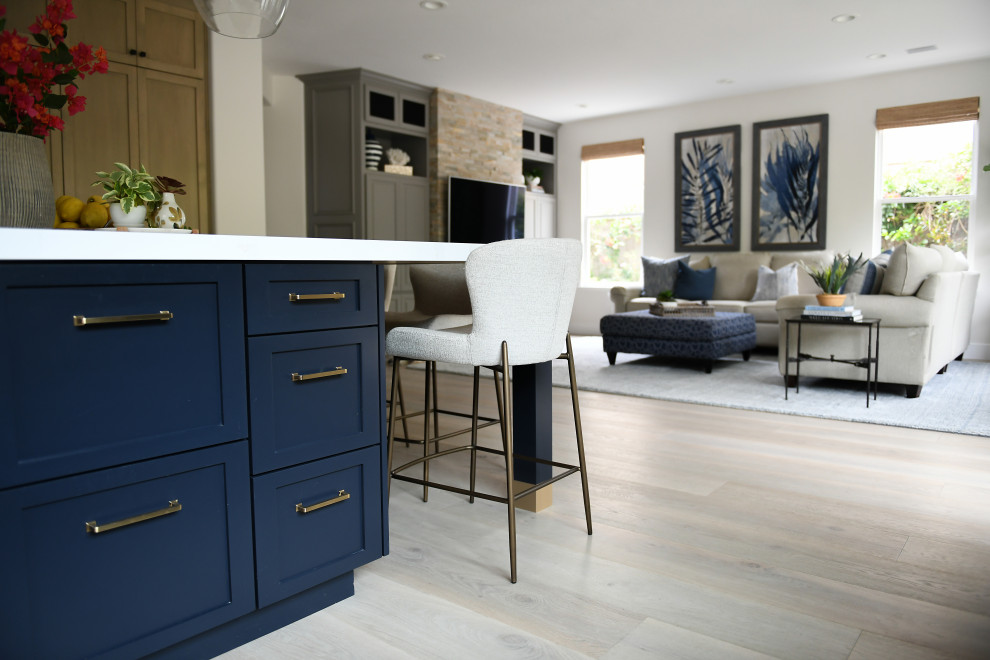 Example of a large medium tone wood floor and brown floor kitchen design in San Diego with a farmhouse sink, shaker cabinets, light wood cabinets, quartz countertops, blue backsplash, terra-cotta backsplash, paneled appliances, an island and white countertops