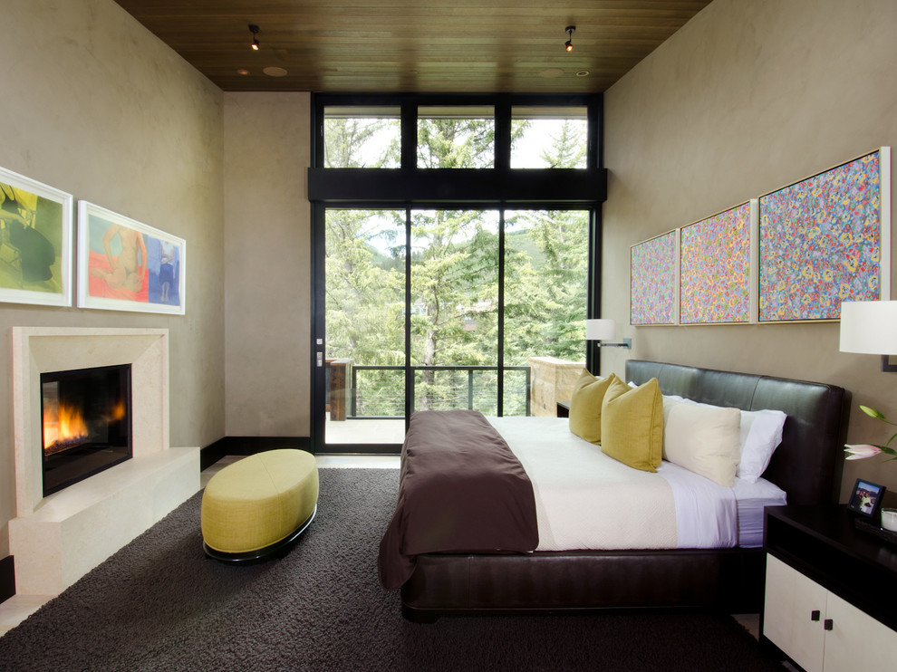 Design ideas for a contemporary bedroom in Denver with beige walls, light hardwood floors and a standard fireplace.