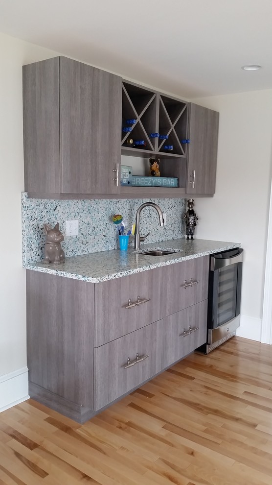 Design ideas for a mid-sized beach style single-wall wet bar in Boston with an undermount sink, flat-panel cabinets, grey cabinets, recycled glass benchtops, blue splashback and light hardwood floors.