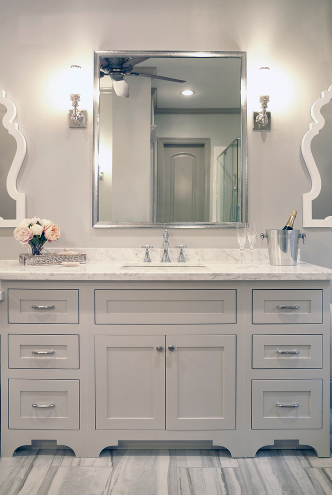 Photo of a large transitional master bathroom in Houston with shaker cabinets, beige cabinets, a freestanding tub, a corner shower, gray tile, white tile, ceramic tile, beige walls, porcelain floors, an undermount sink and quartzite benchtops.