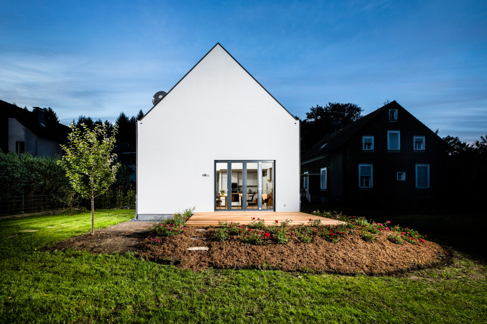 Mid-sized minimalist gray split-level stucco house exterior photo in Dortmund with a tile roof and a black roof
