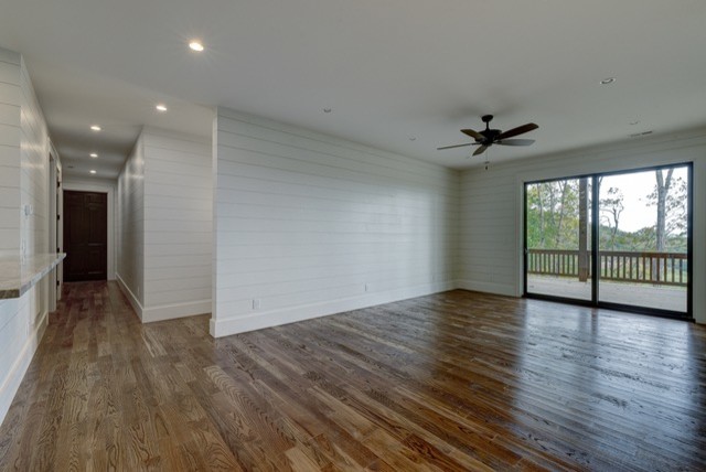 Example of a large mountain style walk-out medium tone wood floor and brown floor basement design with white walls and no fireplace