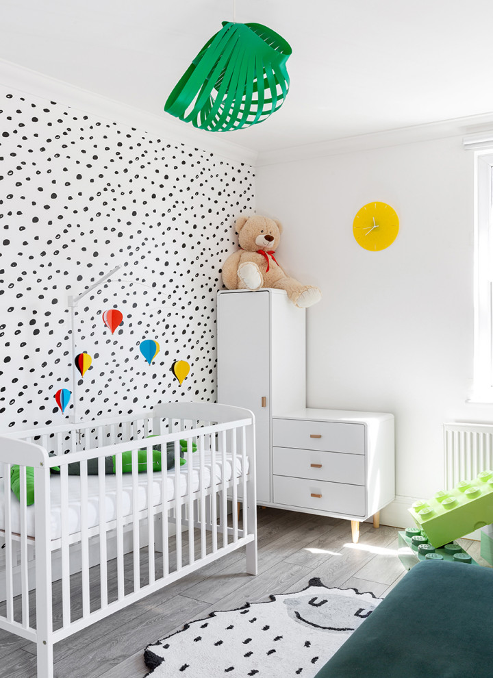 This is an example of a mid-sized scandinavian gender-neutral nursery in London with multi-coloured walls, light hardwood floors, grey floor and wallpaper.