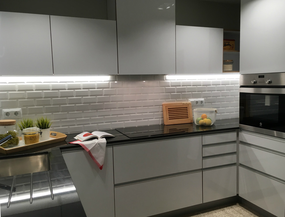 Inspiration for a mid-sized transitional u-shaped separate kitchen in Barcelona with an undermount sink, flat-panel cabinets, white cabinets, granite benchtops, white splashback, subway tile splashback, stainless steel appliances and terrazzo floors.