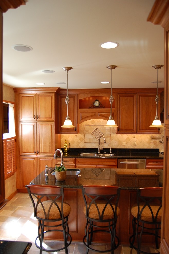 Large traditional galley eat-in kitchen in Baltimore with a double-bowl sink, raised-panel cabinets, medium wood cabinets, granite benchtops, beige splashback, travertine splashback, stainless steel appliances, travertine floors, with island, beige floor and black benchtop.
