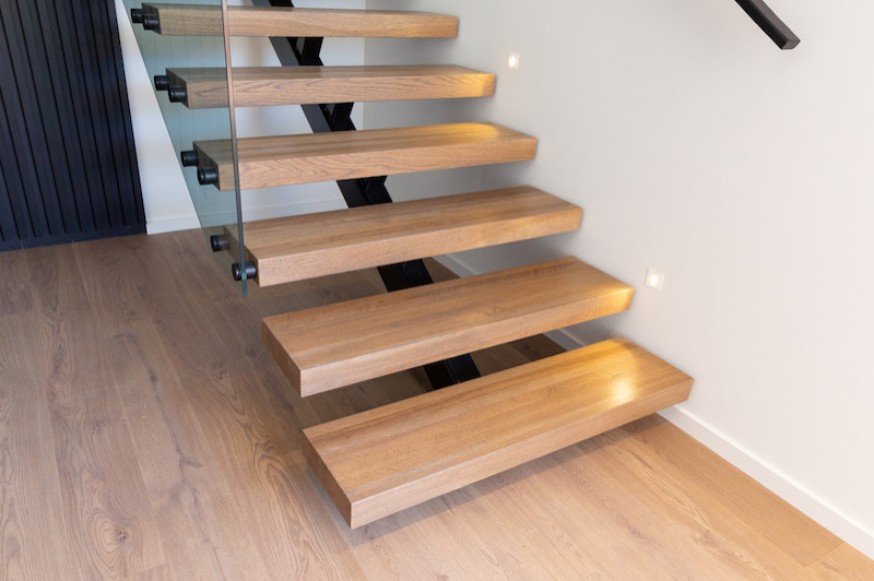 На фото: лестница на больцах, среднего размера в стиле модернизм с деревянными ступенями и металлическими перилами без подступенок с