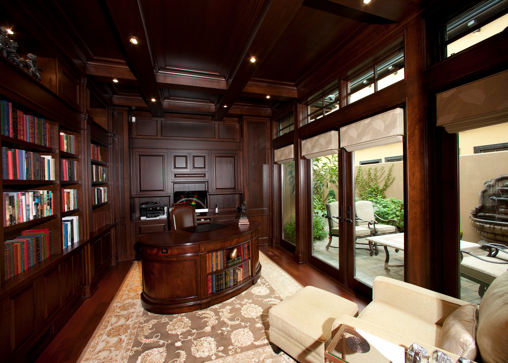 This is an example of a large traditional home office in Other with a library, red walls, medium hardwood floors, no fireplace, a freestanding desk and red floor.