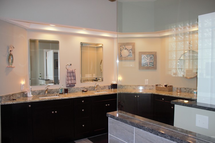Photo of a mid-sized beach style master bathroom in Jacksonville with shaker cabinets, dark wood cabinets, a curbless shower, a two-piece toilet, gray tile, white walls, porcelain floors, an undermount sink and granite benchtops.
