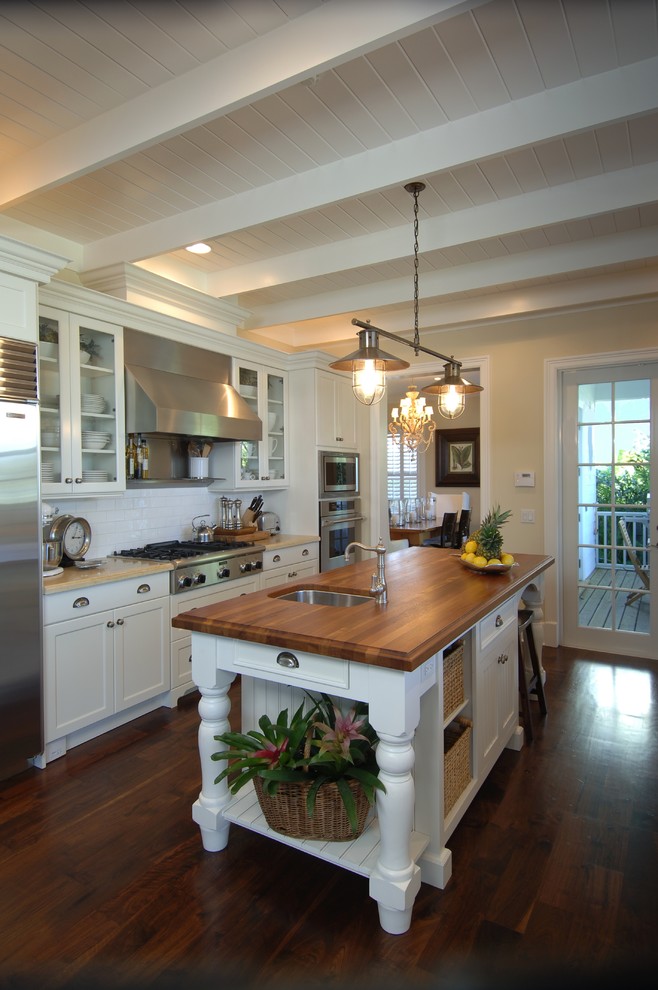 Inspiration for a mid-sized traditional galley separate kitchen in Miami with subway tile splashback, wood benchtops, white cabinets, white splashback, stainless steel appliances, a single-bowl sink, shaker cabinets, dark hardwood floors and with island.