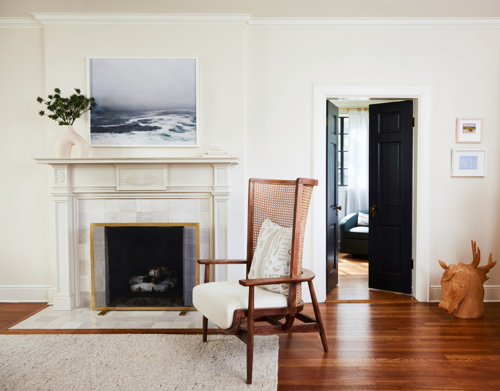 Foto di un soggiorno di medie dimensioni e chiuso con pareti beige, pavimento in legno massello medio, cornice del camino piastrellata e TV nascosta