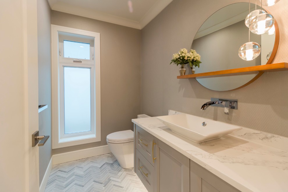 Design ideas for a transitional powder room in Vancouver with recessed-panel cabinets, grey cabinets, a one-piece toilet, white walls, marble floors, a vessel sink and grey floor.
