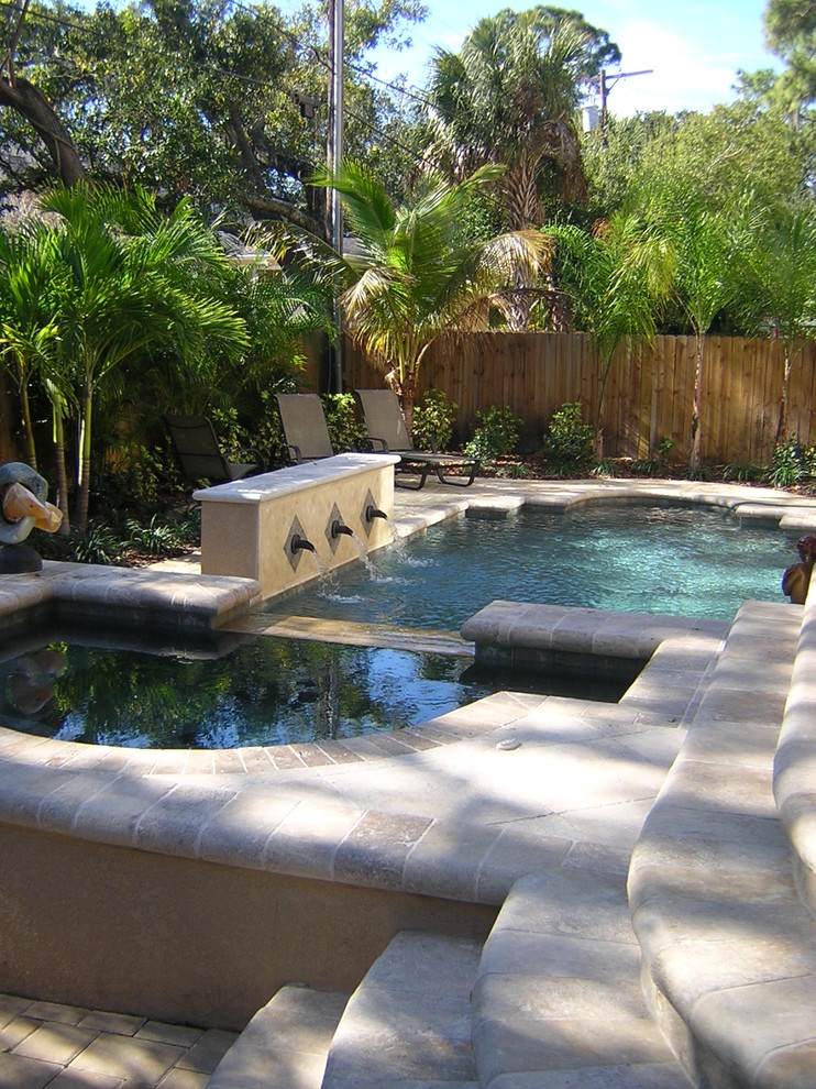 Inspiration for a mid-sized transitional backyard custom-shaped pool in Tampa with a water feature and natural stone pavers.