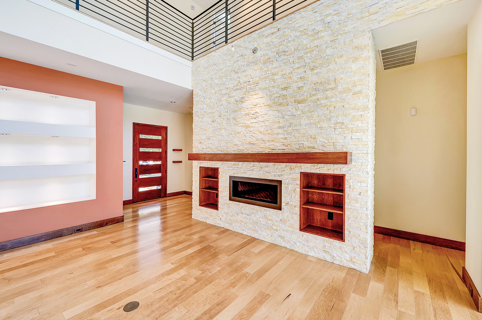 Photo of a modern family room in Dallas with medium hardwood floors, a standard fireplace, a stone fireplace surround and pink walls.