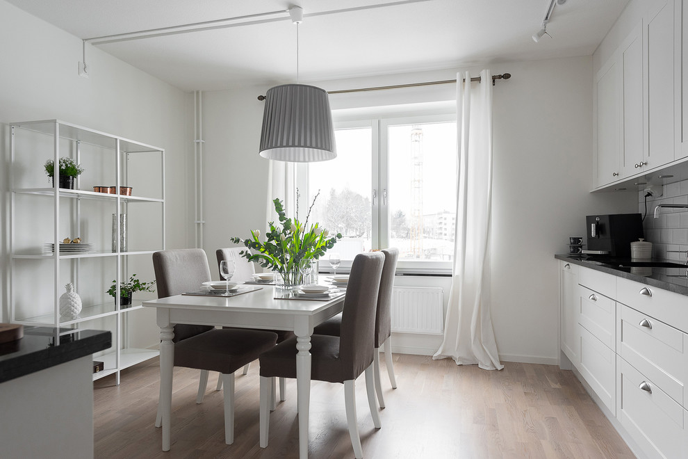 Design ideas for a mid-sized scandinavian kitchen/dining combo in Stockholm with white walls and light hardwood floors.