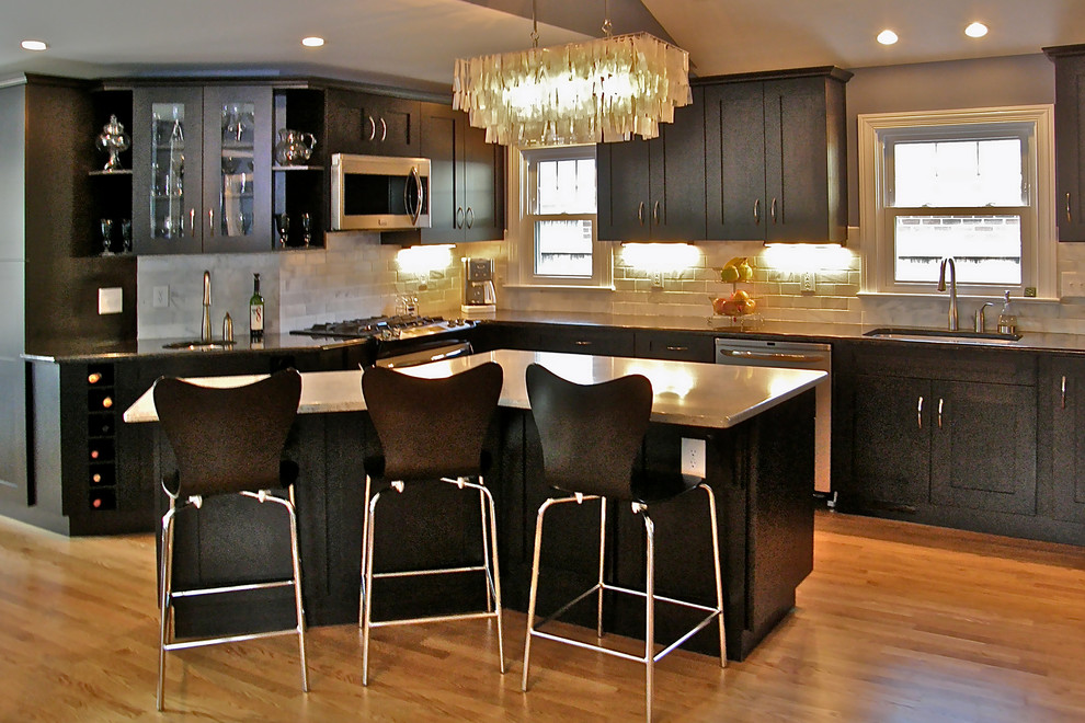 Eat-in kitchen - mid-sized modern l-shaped light wood floor eat-in kitchen idea with a single-bowl sink, flat-panel cabinets, dark wood cabinets, granite countertops, gray backsplash, stone tile backsplash, stainless steel appliances and an island