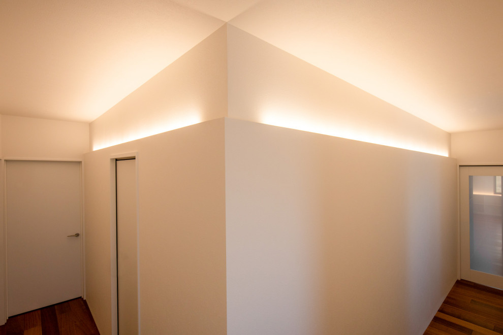 Idée de décoration pour un grand couloir minimaliste avec un mur blanc, parquet foncé, un sol marron, un plafond en papier peint et du papier peint.
