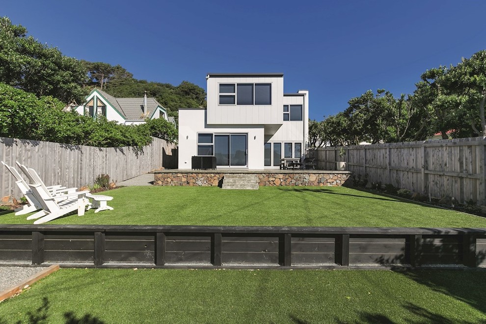 This is an example of a large contemporary two-storey grey house exterior in Wellington with a flat roof and a metal roof.