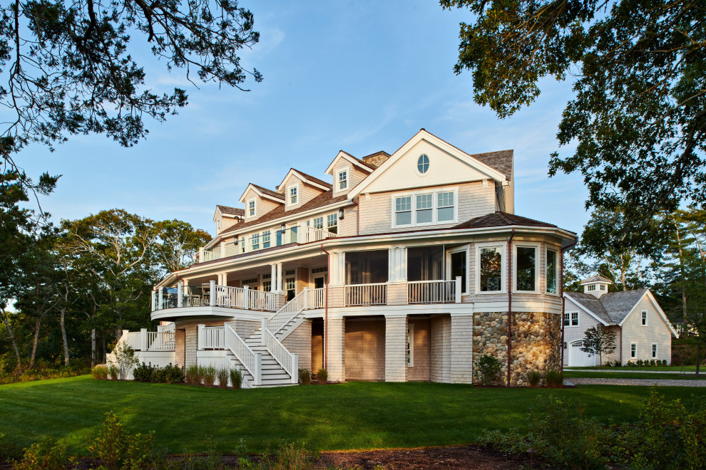 Photo of a beach style three-storey exterior in Boston with wood siding, a butterfly roof, a shingle roof and shingle siding.