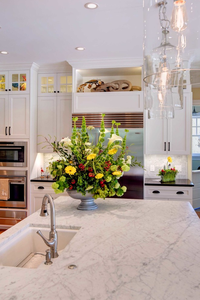 Eat-in kitchen - transitional medium tone wood floor eat-in kitchen idea with an undermount sink, shaker cabinets, white cabinets, marble countertops, gray backsplash, subway tile backsplash, stainless steel appliances and an island
