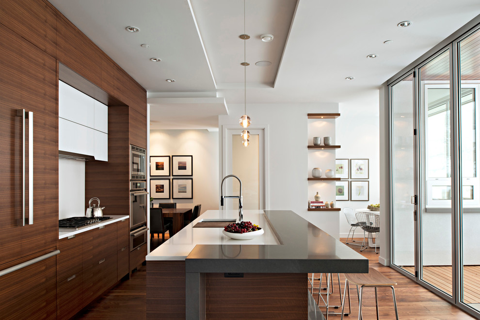 Design ideas for a contemporary galley open plan kitchen in Vancouver with an undermount sink, flat-panel cabinets, dark wood cabinets, white splashback and glass sheet splashback.