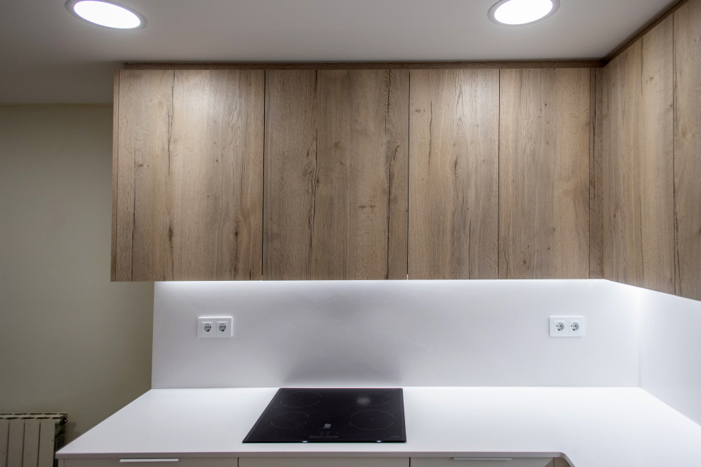 Photo of a mid-sized contemporary l-shaped separate kitchen in Barcelona with a single-bowl sink, flat-panel cabinets, medium wood cabinets, white splashback, stainless steel appliances, ceramic floors, no island, brown floor and white benchtop.