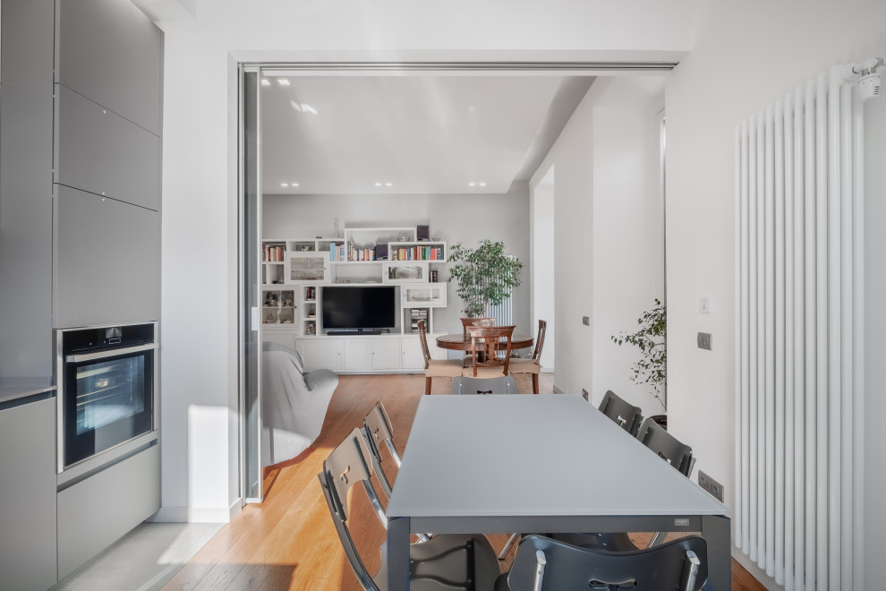 Design ideas for an expansive contemporary l-shaped kitchen/diner in Rome with a submerged sink, flat-panel cabinets, grey cabinets, marble worktops, grey splashback, porcelain splashback, black appliances, porcelain flooring, a breakfast bar, grey floors, grey worktops and a drop ceiling.