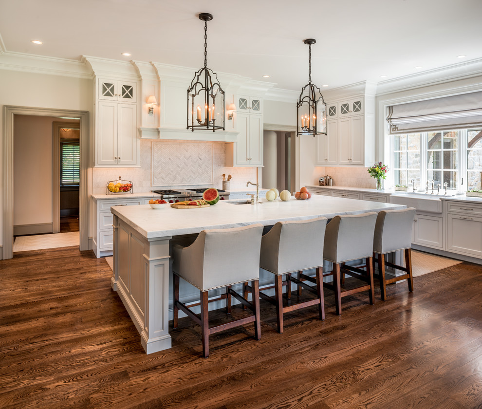 Large traditional u-shaped open plan kitchen in Wilmington with a farmhouse sink, recessed-panel cabinets, white cabinets, marble benchtops, grey splashback, marble splashback, stainless steel appliances, dark hardwood floors, with island and brown floor.