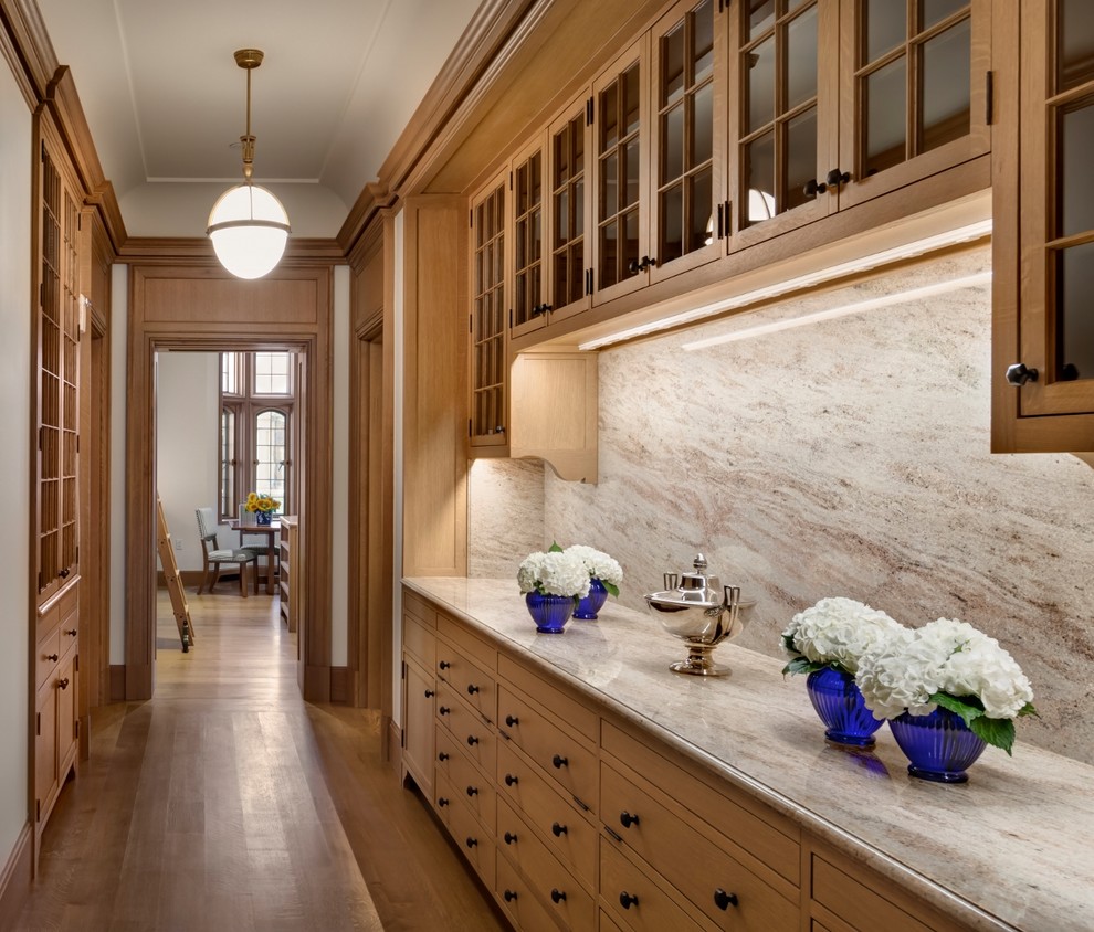 This is an example of an expansive traditional galley kitchen pantry in Bridgeport with a farmhouse sink, glass-front cabinets, medium wood cabinets, stainless steel appliances, medium hardwood floors, with island and brown floor.