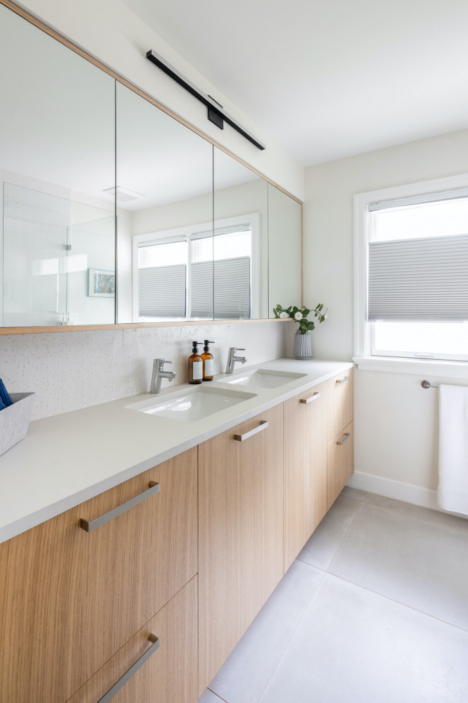 Aménagement d'une salle de bain contemporaine en bois clair de taille moyenne avec un placard à porte plane, un carrelage blanc, des carreaux de céramique, un plan de toilette en quartz modifié, un plan de toilette gris, meuble double vasque et meuble-lavabo encastré.