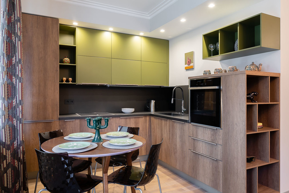 Mid-sized contemporary l-shaped eat-in kitchen in Saint Petersburg with an undermount sink, flat-panel cabinets, medium wood cabinets, quartzite benchtops, black splashback, stainless steel appliances, medium hardwood floors, no island and black benchtop.