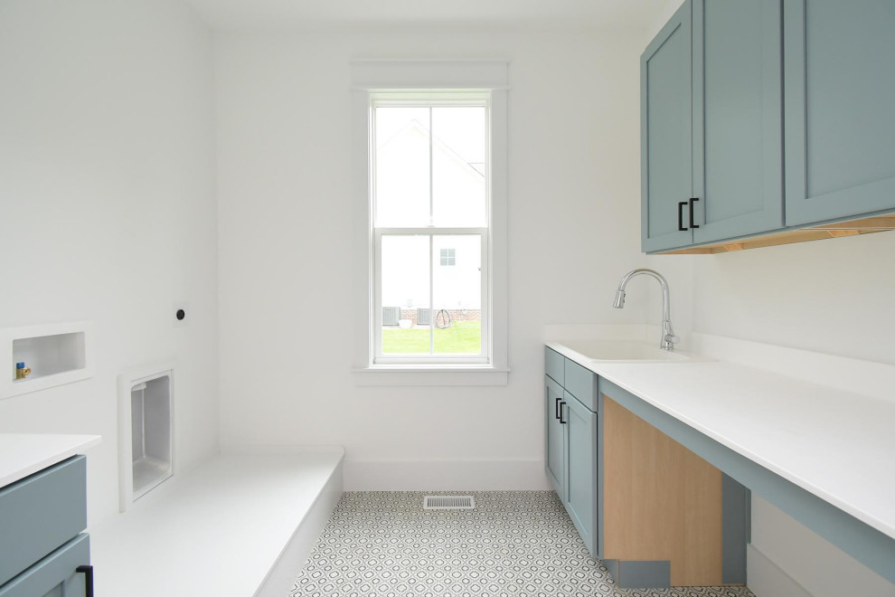 Photo of a large traditional galley dedicated laundry room in Raleigh with an utility sink, shaker cabinets, blue cabinets, marble benchtops, white splashback, marble splashback, white walls, ceramic floors, a side-by-side washer and dryer, multi-coloured floor and white benchtop.