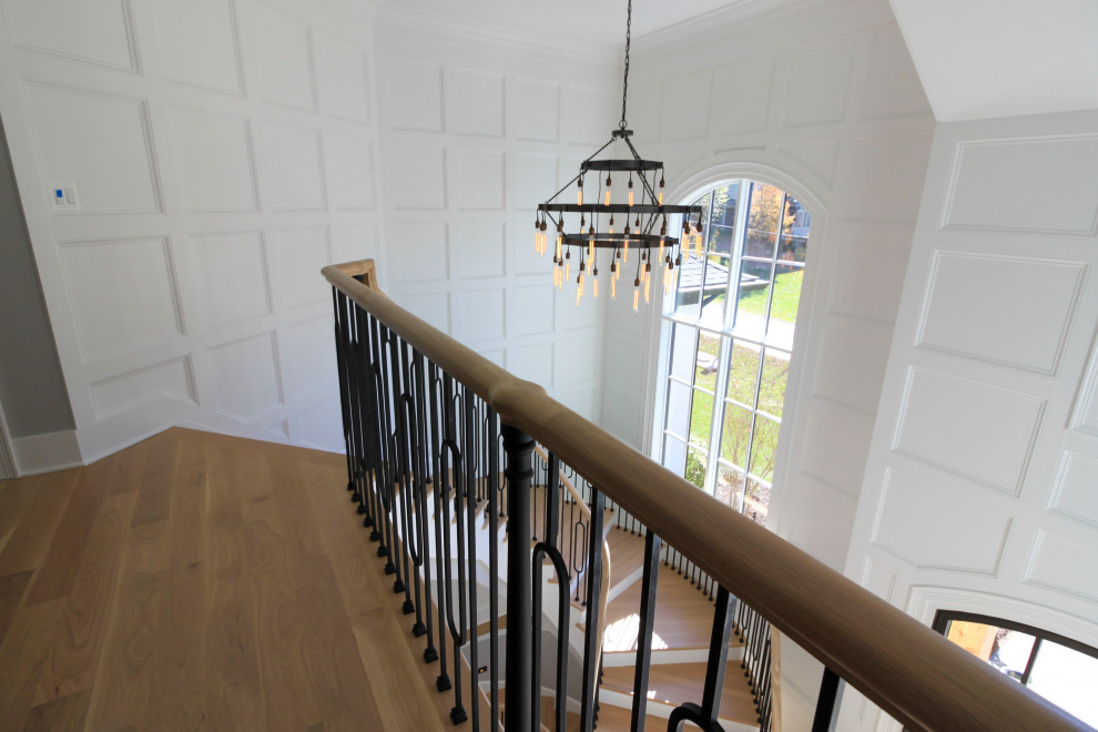 Huge transitional wooden curved mixed material railing and wainscoting staircase photo in DC Metro with wooden risers
