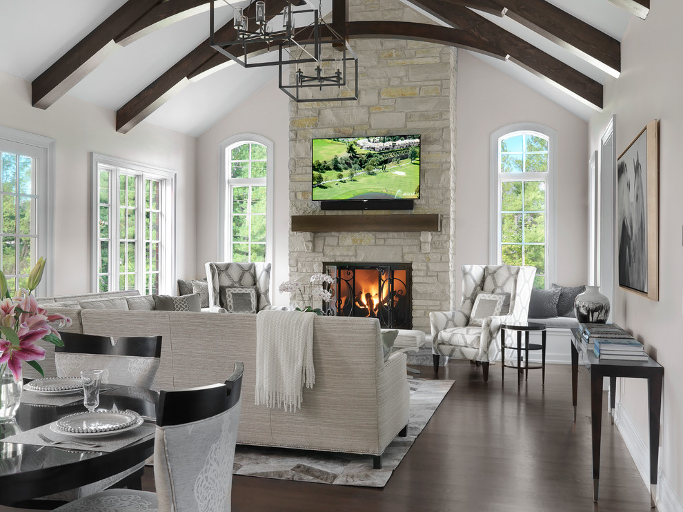 Photo of a traditional living room in St Louis with white walls, dark hardwood floors, a standard fireplace, a stone fireplace surround, a wall-mounted tv and brown floor.