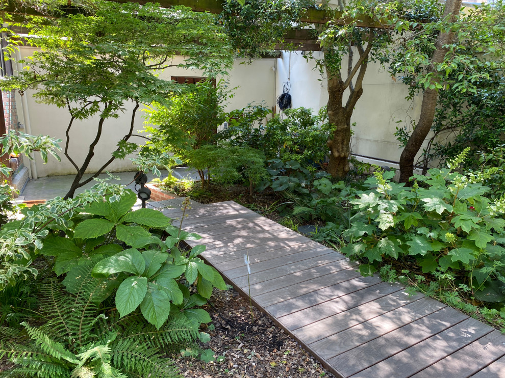 Exemple d'un petit jardin avant nature au printemps avec une exposition partiellement ombragée et une terrasse en bois.
