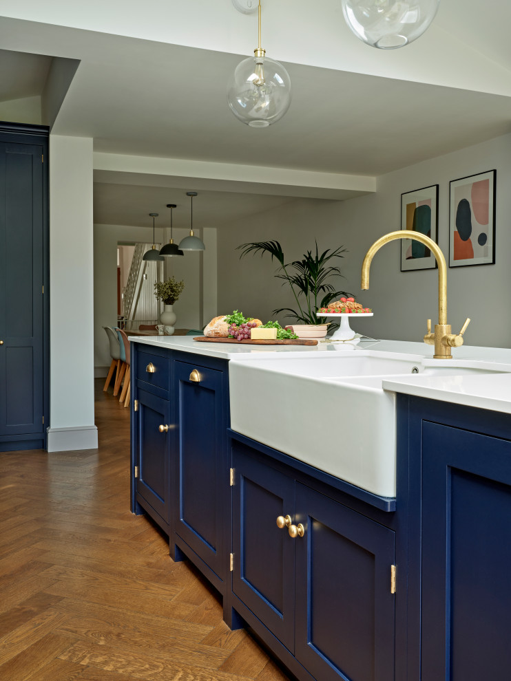 Large transitional single-wall eat-in kitchen in London with shaker cabinets, with island, a farmhouse sink, blue cabinets, quartzite benchtops, white splashback, ceramic splashback, panelled appliances, white benchtop and vaulted.