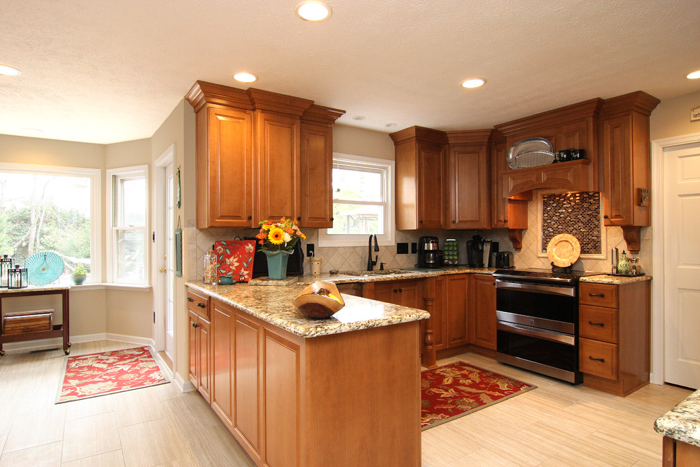 Example of a large transitional u-shaped porcelain tile eat-in kitchen design with an undermount sink, raised-panel cabinets, medium tone wood cabinets, granite countertops, beige backsplash, porcelain backsplash and stainless steel appliances