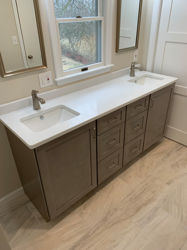Medium sized modern ensuite bathroom in New York with shaker cabinets, grey cabinets, an alcove bath, a shower/bath combination, a two-piece toilet, grey tiles, porcelain tiles, porcelain flooring, a submerged sink, quartz worktops, a wall niche, double sinks and a freestanding vanity unit.